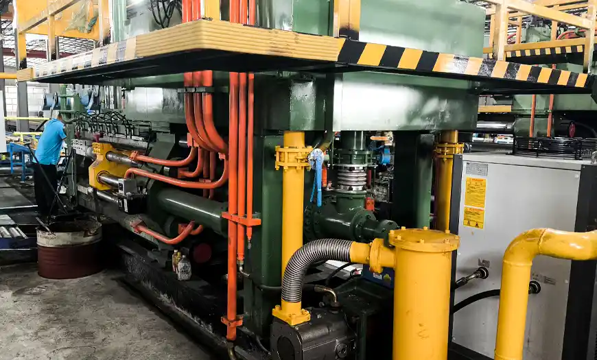 Heavy-duty green hydraulic aluminum extrusion press machine with industrial piping and cooling system in the manufacturing plant