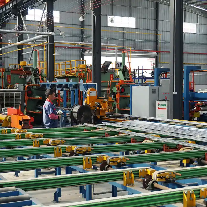 Operator monitoring the aluminum billet heating and automated extrusion line in the manufacturing plant.