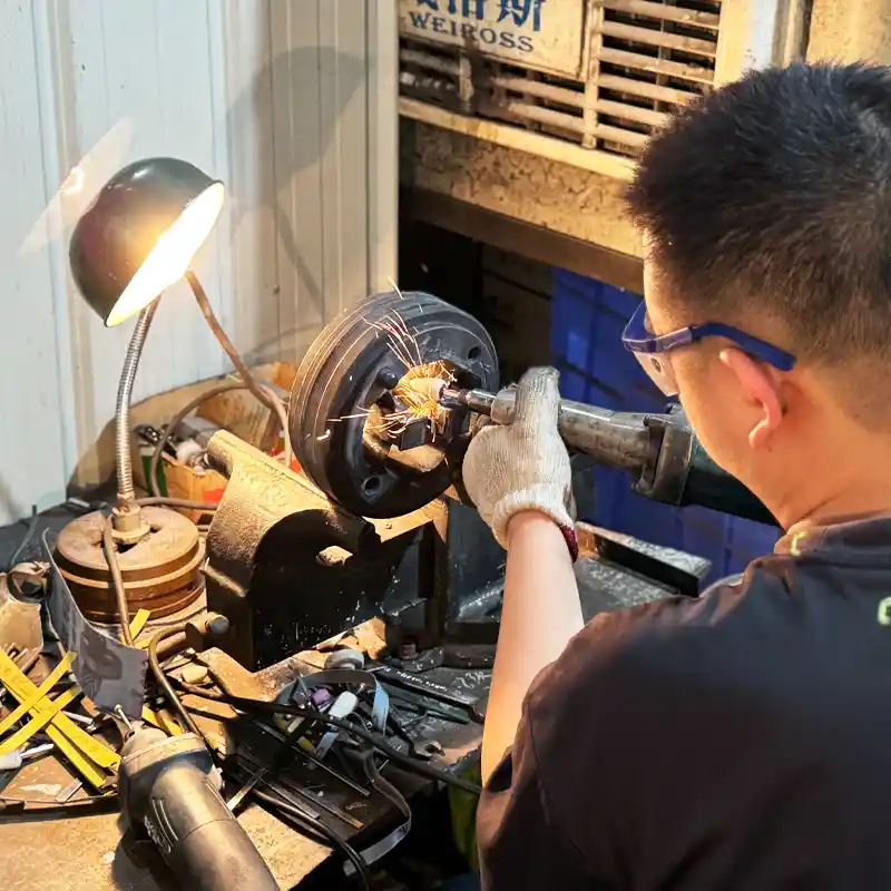 Technician wearing safety glasses using an angle grinder to modify a heavy aluminum extrusion die.