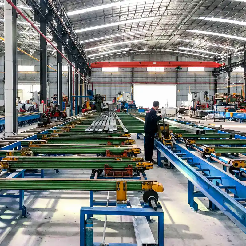 Automated runout table and cooling bed processing freshly extruded aluminum profiles in a large workshop.