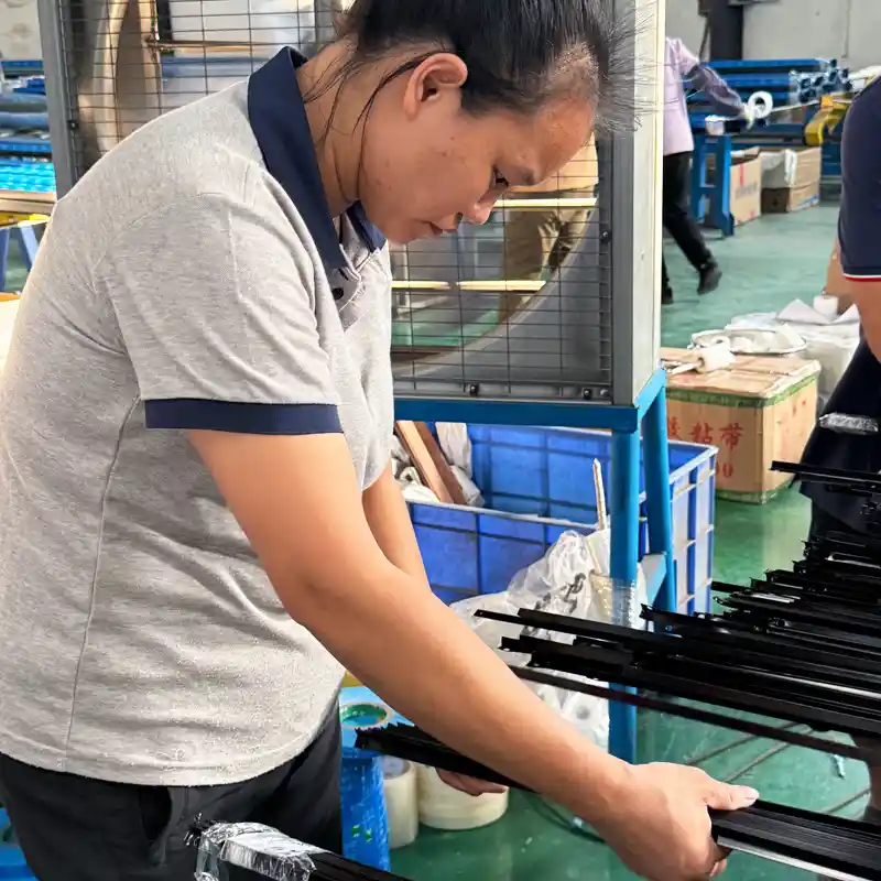 Quality control inspector examining black anodized aluminum profiles before final packaging.