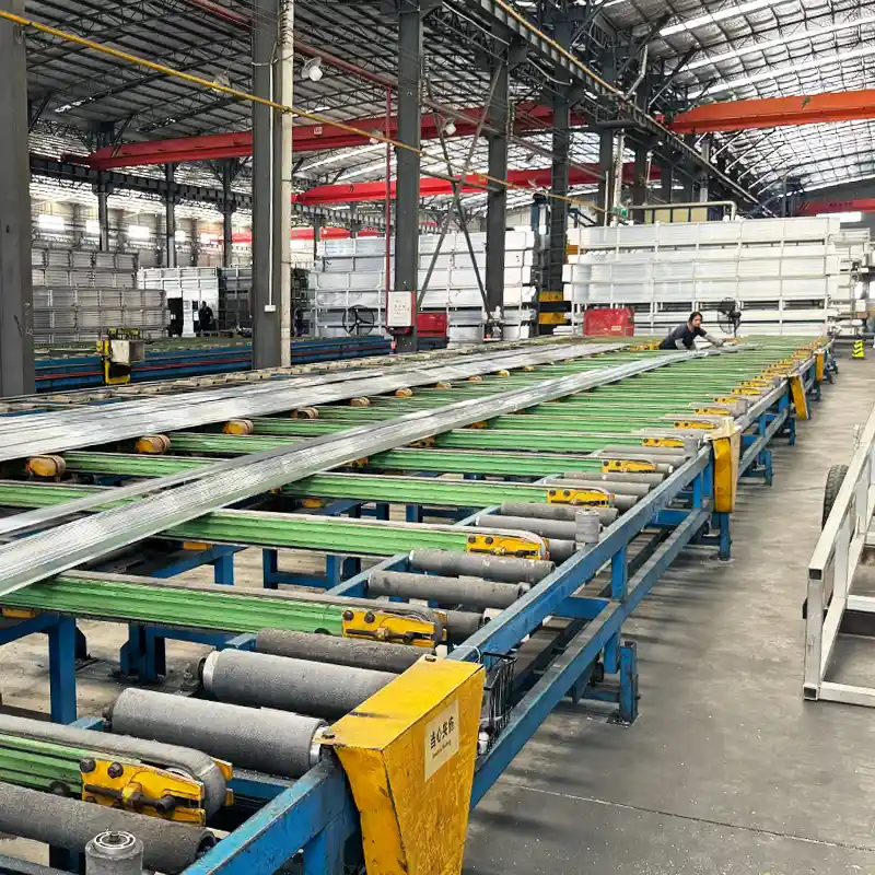 Extra-long extruded aluminum profiles moving along an automated runout table in the extrusion workshop.