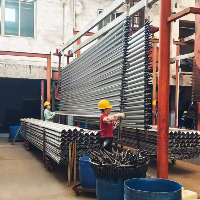 Female workers loading round aluminum tubes onto a large vertical rack for anodizing and surface treatment.